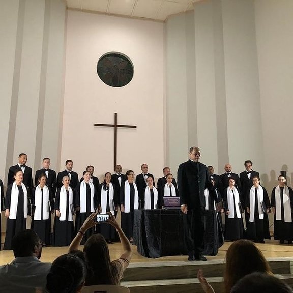 Coralistas em traje preto e branco, apresentação solene em igreja